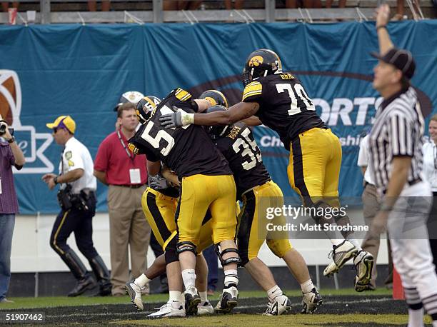 Offensive linemen Lee Gray, Mike Elgin and fullback Tom Busch of the Iowa Hawkeyes celebrate the game-winning touchdown reception by wide receiver...