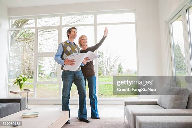 couple holding building plans and discussing remodel - perfect home stock pictures, royalty-free photos & images