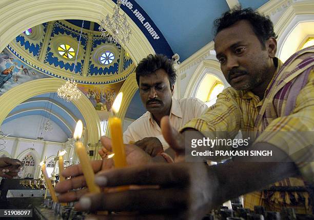 Indian devotees Krishna and Rajkumar light candles after a special prayer meeting for tsunami victims at the Basilica Shrine in Velankanni 365 kms...