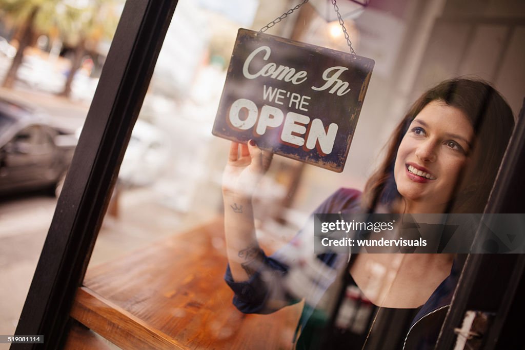 Mujer de negocios dueño de giro de señal de puerta de apertura en la cafetería