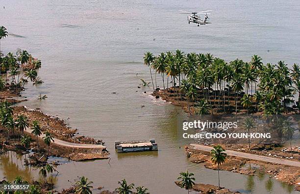 Navy helicopter Seahawk flies over a damaged road, in Teunom, 170 km southwest from Banda Aceh, in Aceh province, Indonesia 02 January 2005, seven...