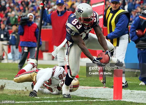 Deion Branch of the New England Patriots scores a touchdown as Dwaine Carpenter of the San Francisco 49ers misses the tackle during their game on...