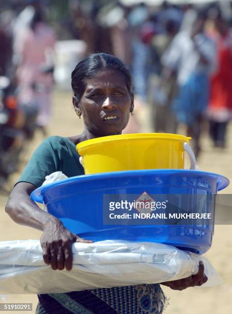 Homeless Sri Lankan tsunami survivor carries back non food relief item at the central college camp in the Liberation Tigers of Tamil Eelam controlled...