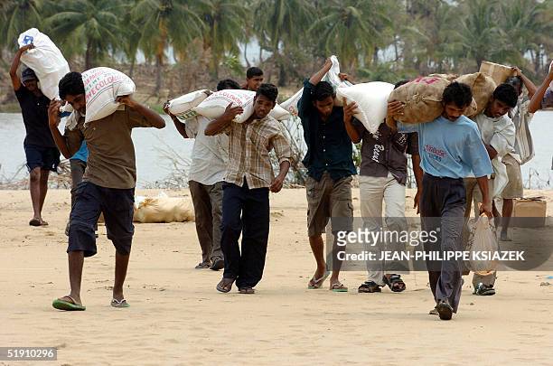 Sri Lankan victims of the 26 December deadly tsunamis carry sacks of relief food distributed by Sri Lankan special forces, 03 January 2005 in...