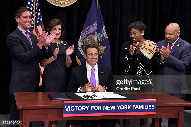 New York Gov. Andrew Cuomo, center, is applauded after he signed a law that will gradually raise New York's minimum wage to $15, at the Javits...