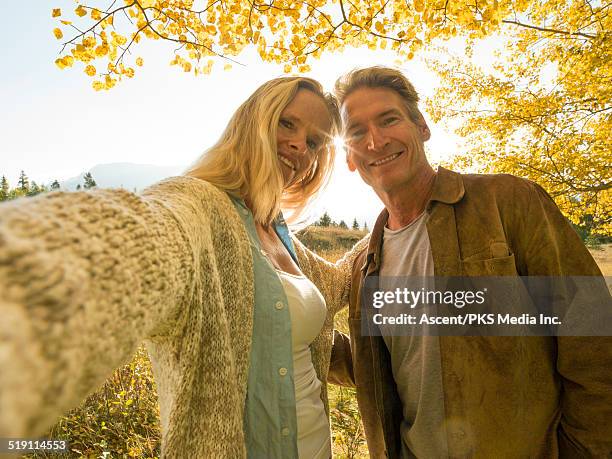 couple take selfie under autumn leaves, mtn - sun flare couple stockfoto's en -beelden