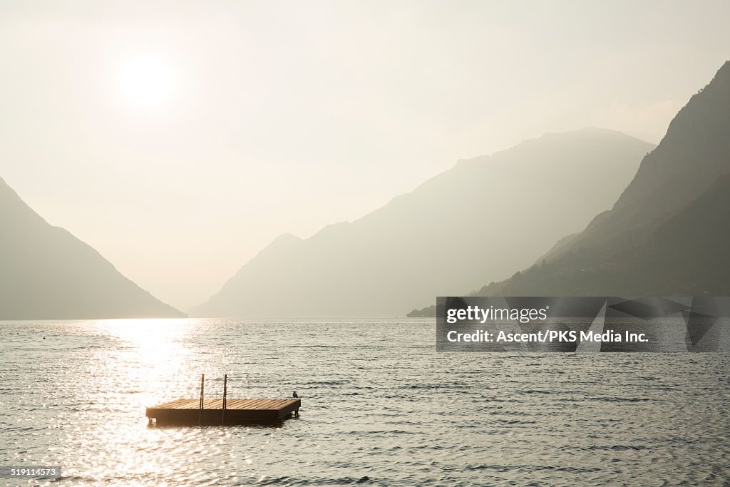 Raft bobs on tranquil lake, below mountains