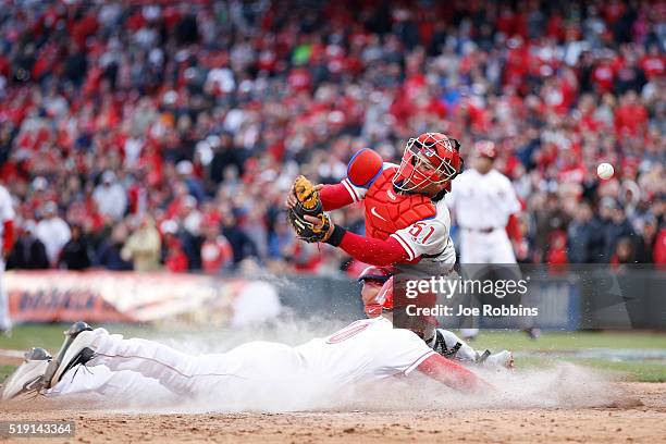 Tyler Holt of the Cincinnati Reds slides home with the tying run ahead of the throw to Carlos Ruiz of the Philadelphia Phillies after a sacrifice fly...