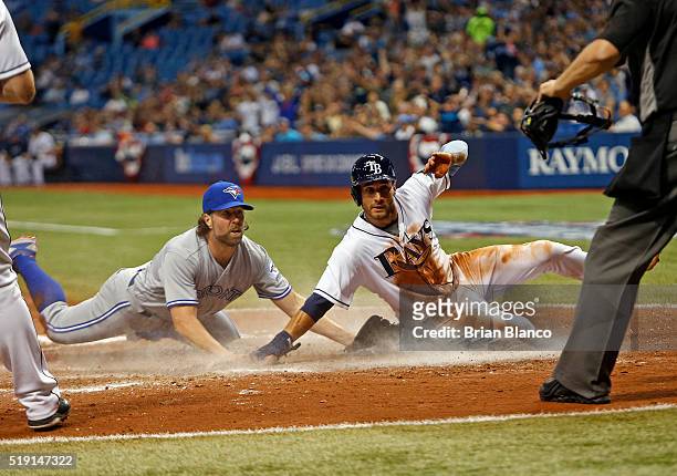 Kevin Kiermaier of the Tampa Bay Rays slides across home plate ahead of pitcher R.A. Dickey of the Toronto Blue Jays to score off Dickey's wild pitch...