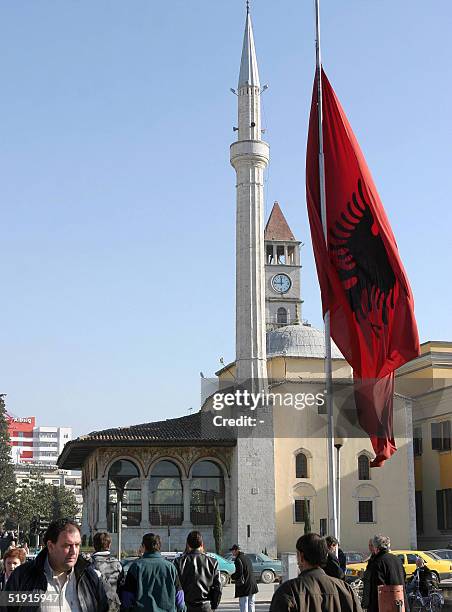 Albanian citizens past next to an Albanian flag flying at half-mast in the Tirana's central square, on the national day of mourning for tsunami...