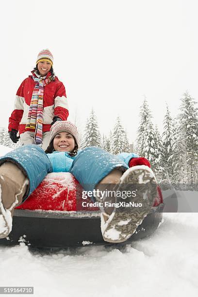 mother and daughter with snow tube - snow tubing stock pictures, royalty-free photos & images