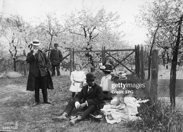 American boxer Jack Johnson , the world heavyweight champion, on a picnic with an unidentified party among orchard blossoms, Berlin, Germany, mid...