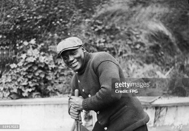 American boxer Jack Johnson , the world heavyweight champion, grips an unidentified apparatus, San Francisco, California, early 1910s.