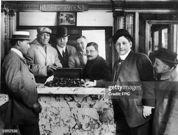 American boxer Jack Johnson , the world heavyweight champion, and his manager, George Little open a chest of coins at a bank, late 1900s to early...