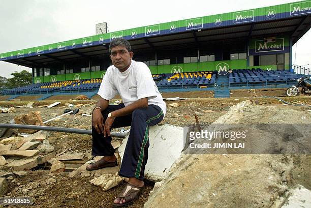 Sri Lankan cricket figure Jayananda Warnaweera sits on the rubble strewn all over the cricket pitch at the Galle international cricket stadium in the...