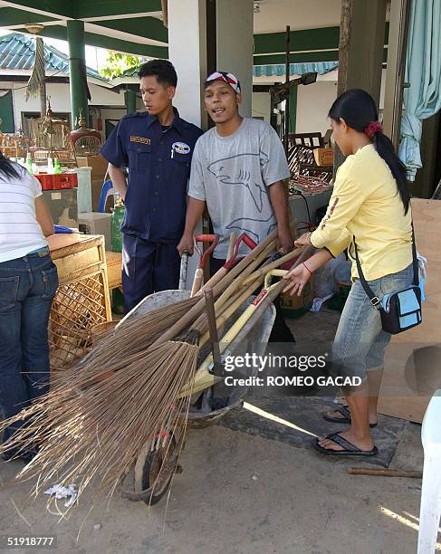 Hotel workers carry broom sticks and shovels, 06 January 2005, to clean up the debris from the damaged hotel along the beach road of Patong beach in...