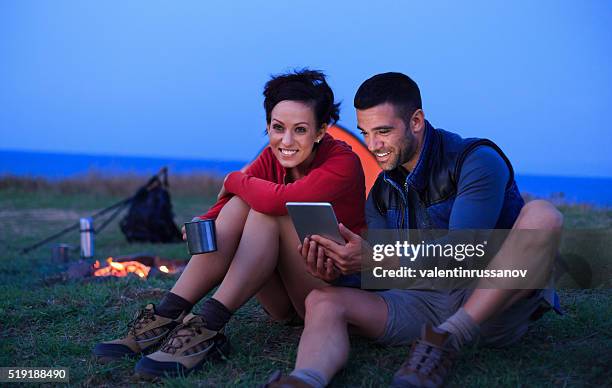 giovane coppia di riposo nella parte anteriore di tenda e falò - twilight foto e immagini stock