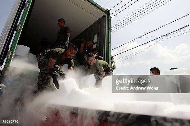 Thai soldiers unload dry ice in order to preserve the bodies of tsunami victims at a make-shift morgue at a temple on January 6, 2005 in Takua Pa,...