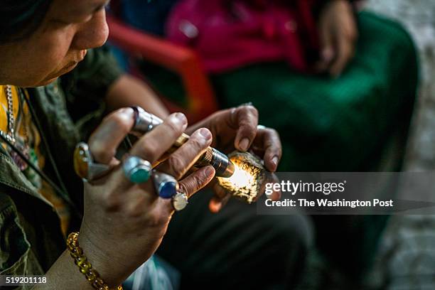 13th, 2016: A jade trader in a local tea shop examines the quality of a raw stone with a light.