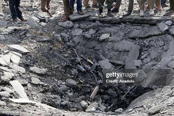 People gather around a hole at the site of a car bombing attack killing at least two people and injuring six at a market in Maarat al-Numan of Idlib,...