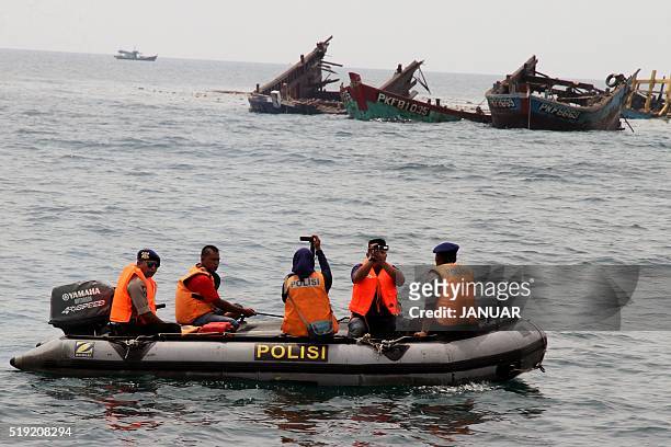 Police on a boat are seen past the remnants of illegal fishing boats blown up with explosives by Indonesian authorities in Kuala Langsa, Aceh...