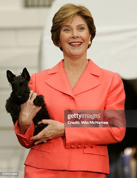 First lady Laura Bush carries Miss Beazley, the Scottish Terrier pup given to her as a birthday present by U.S. President George W. Bush, during an...