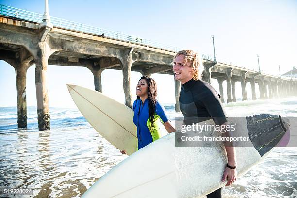 group of people embracing at sunset with surfboard - manhattan beach stock pictures, royalty-free photos & images