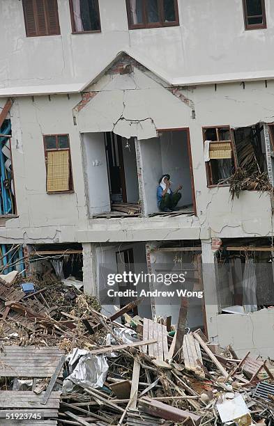 Worker takes a break from retrieving usable items from a destroyed seaside hotel before tearing it down on January 7, 2005 in the resort district of...