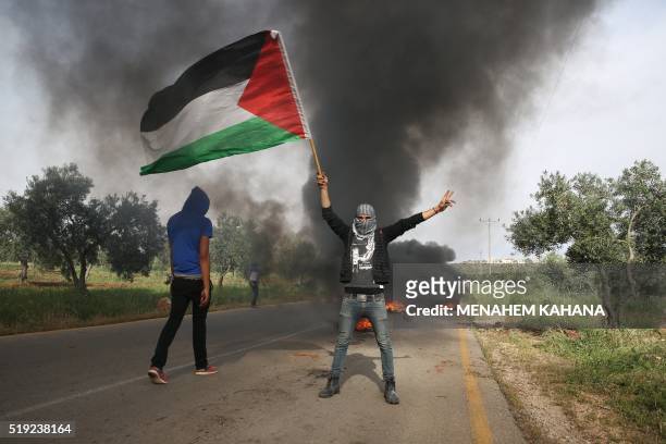 Palestinian demonstrators burn tires during a protest against the nearby demonstration by Israeli right-wing activists calling on Israel to release...