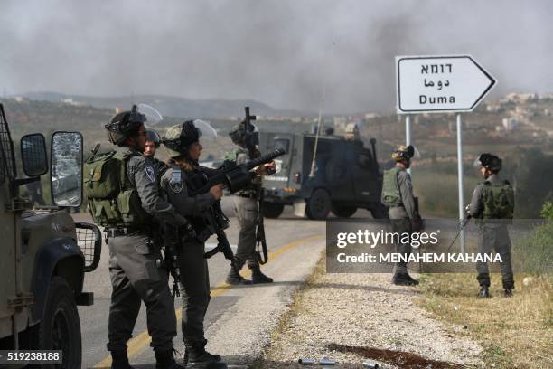 Israeli border police keep watch as Palestinian demonstrators burn tires during a protest against the nearby demonstration by Israeli right-wing...