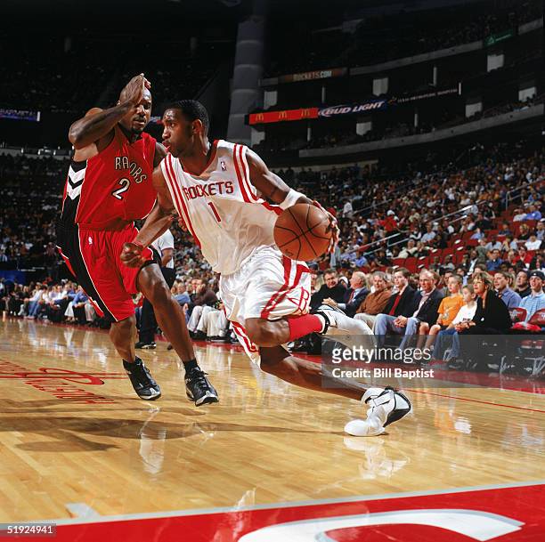 Tracy McGrady of the Houston Rockets drives around Lamond Murray of the Toronto Raptors at Toyota Center on December 20, 2004 in Houston, Texas. The...
