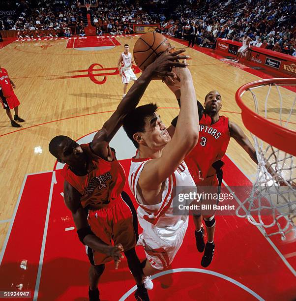 Yao Ming of the Houston Rockets gets blocked as he take the ball to the basket against Chris Bosh and Loren Woods of the Toronto Raptors at Toyota...