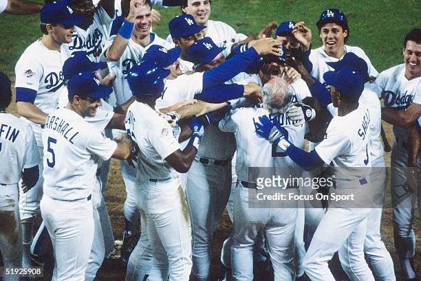 Los Angeles Dodgers teammates rush Kirk Gibson after he hit a home run against the Oakland Athletics during the World Series at Dodger Stadium on...