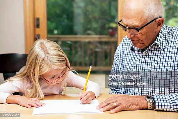 grandfather helping granddaughter with homework - hearing aids stock pictures, royalty-free photos & images
