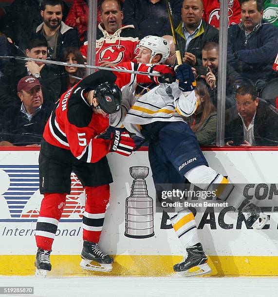 Adam Larsson of the New Jersey Devils checks Jack Eichel of the Buffalo Sabres into the boards during the second period at the Prudential Center on...