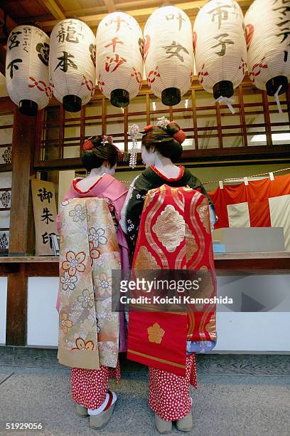 Two Japanese Maikos prepare to tie paper fortunes to a tree on the first business day of the new year at Yasaka Jinja on January 9, 2005 in Kyoto,...