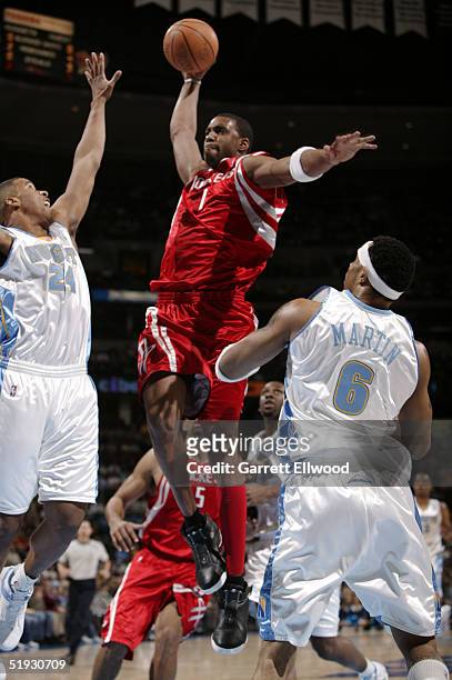 Tracy McGrady of the Houston Rockets dunks over Andre Miller and Kenyon Martin of the Denver Nuggets on January 9, 2005 at Pepsi Center in Denver,...