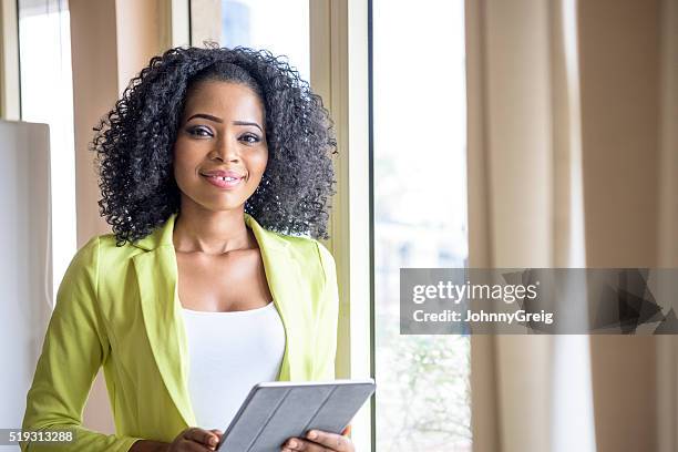 attractive nigerian woman with tablet looking at camera - beautiful nigerian women stock pictures, royalty-free photos & images