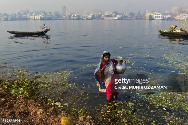 In this photograph taken on March 19 a Bangladeshi woman collects contaminated water to be used on produce at a vegetable market from the polluted...