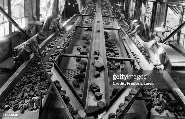 Workers sort through rocks on a conveyor belt, circa 1935.