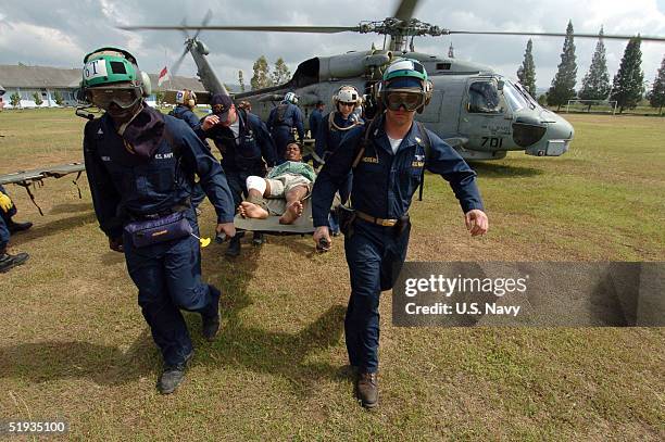 In this handout image provided by the U.S. Navy, Sailors assigned to Carrier Air Wing Two and USS Abraham Lincoln , carry an injured Indonesian from...