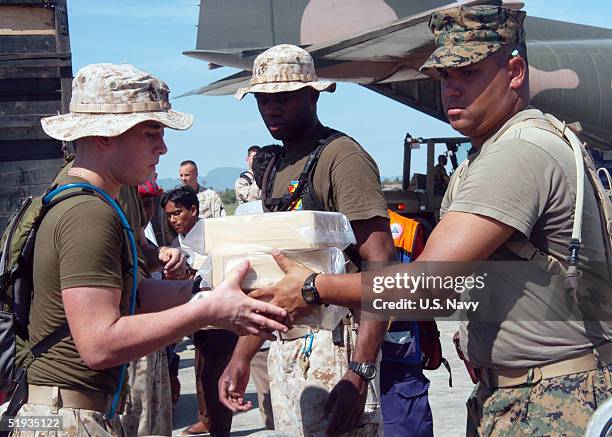 In this handout image provided by the U.S. Navy, U.S. Marines assigned to the 15th Marine Expeditionary Unit , help load medical relief supplies onto...
