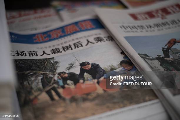 Newspaper shows a front page photo of Chinese leaders including President Xi Jinping attending a tree planting ceremony, at a news stand in Beijing...