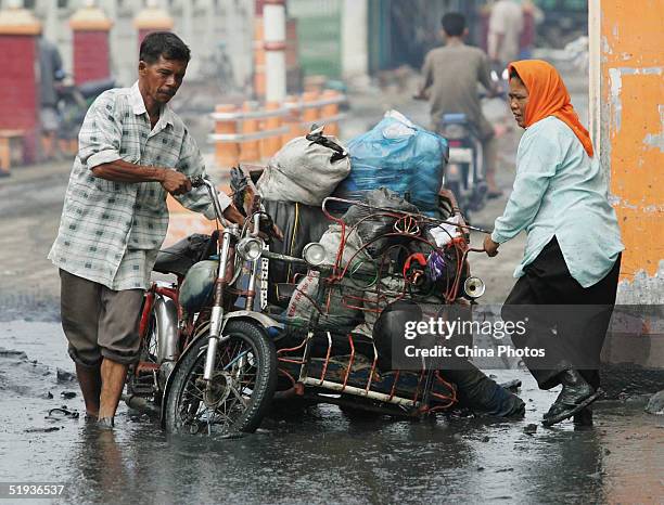 Residents struggle as they transport their belongings on January 10, 2005 in Banda Aceh, Indonesia. The death toll from the earthquake and tsunami in...