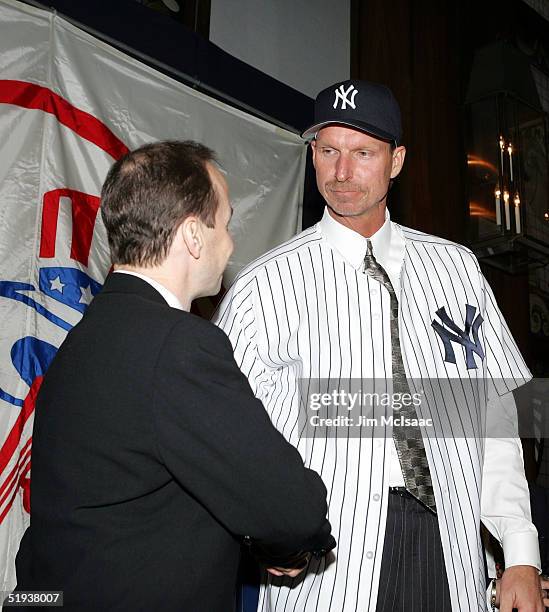 New Yankee pitcher Randy Johnson shakes hands with Yankee general manager Brian Cashman after putting on his new jersey and cap on January 11, 2005...