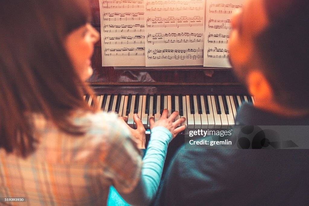 Giovani adulti suona il pianoforte insieme