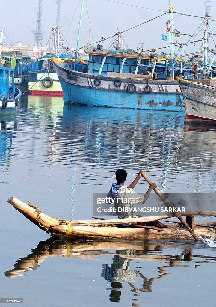 An Indian fisherman rows past an idle fl