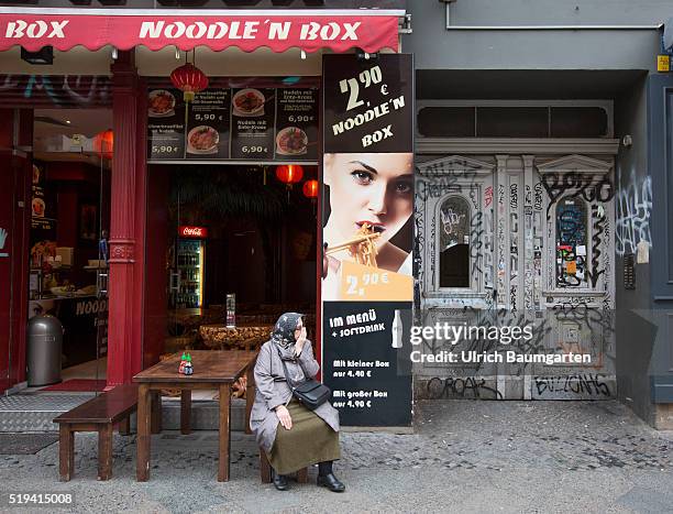 Street scene at Kottbusser Tor, problerm quarter in Berlin-Kreuzberg. Turkish woman in front of a snack bar.