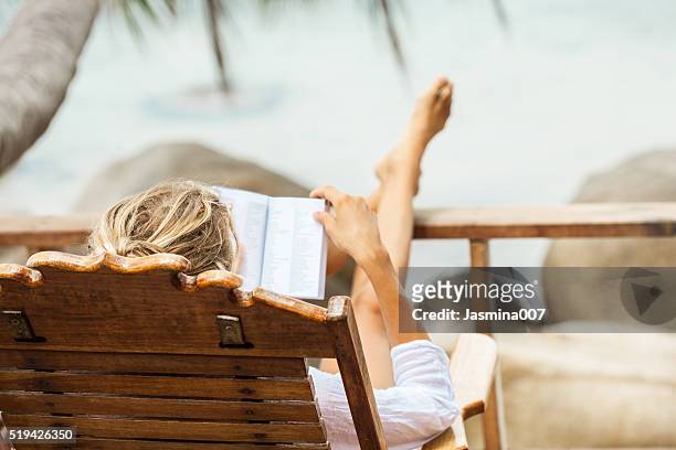 jovem mulher um ler um livro e relaxar na ilha tropical - reading imagens e fotografias de stock