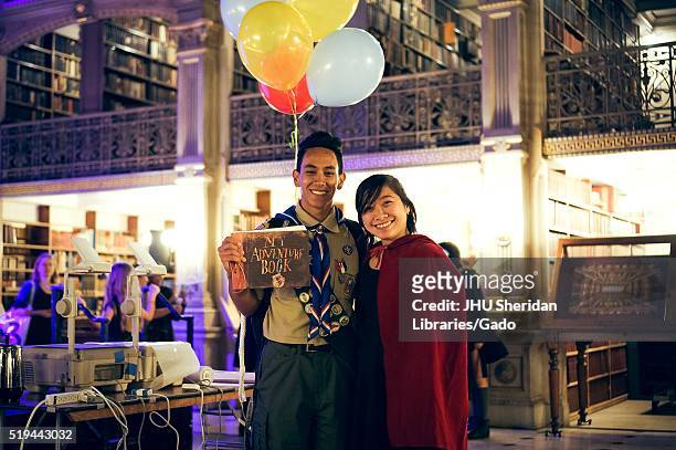Two college students pose with their arms around each other, the boy is dressed as the main character in the Pixar movie "Up" and the girl is wearing...